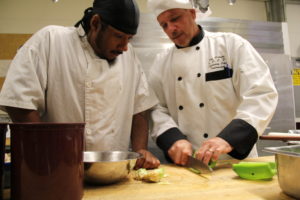 Culinary Faculty demonstrating to student cutting technique