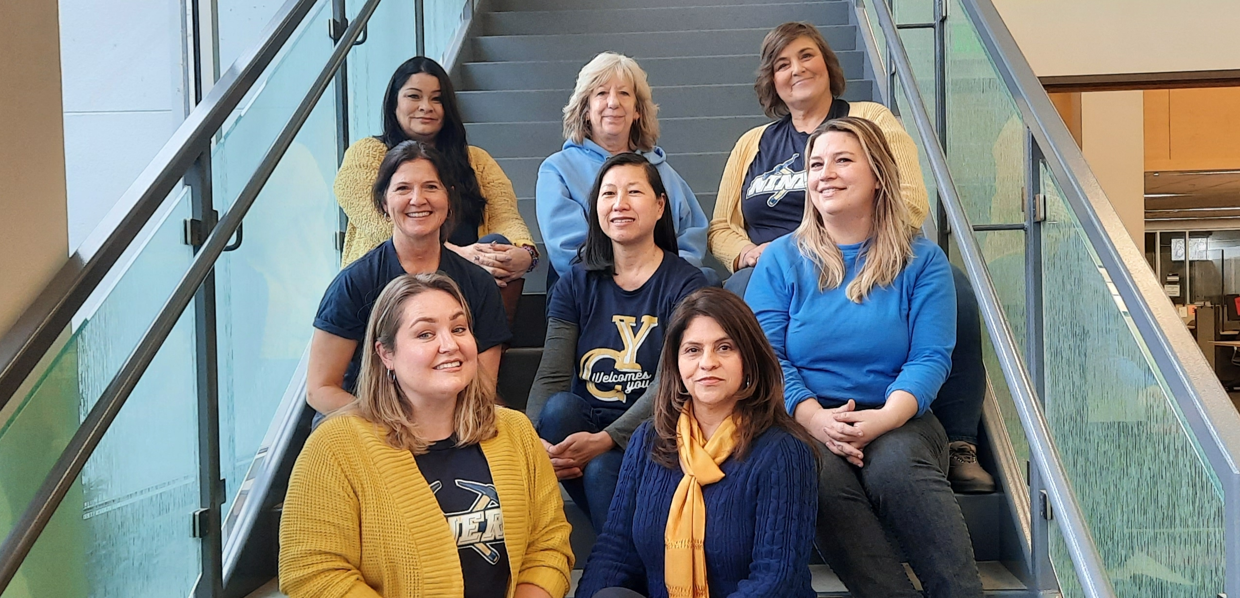 committee members sitting on library stairs wearing blue and gold colors